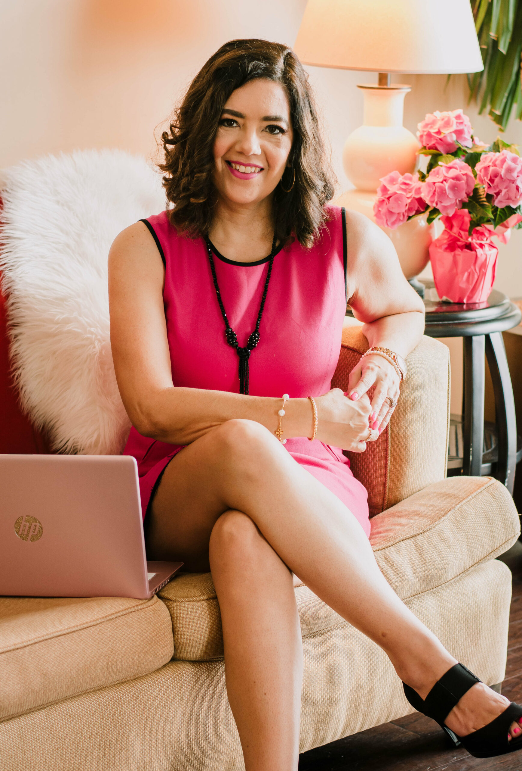 Image of Nancy Brown, a life and business coach, sitting confidently in a large chair, elegantly dressed in a pink attire. The photo captures the essence of her coaching practice, radiating professionalism and empowerment.